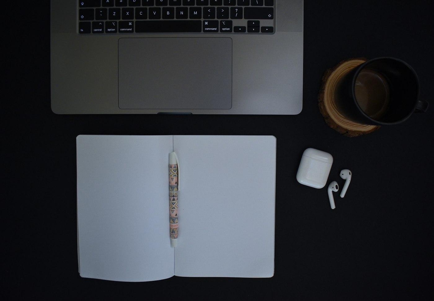Cuaderno y portátil sobre mesa negra para redactar copywriting orientado a conversión