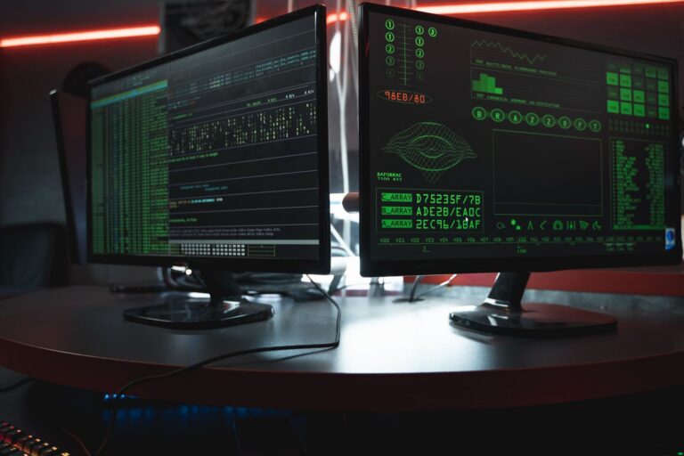 Monitores mostrando código en una pantalla oscura, representando una brecha de seguridad en un servidor
